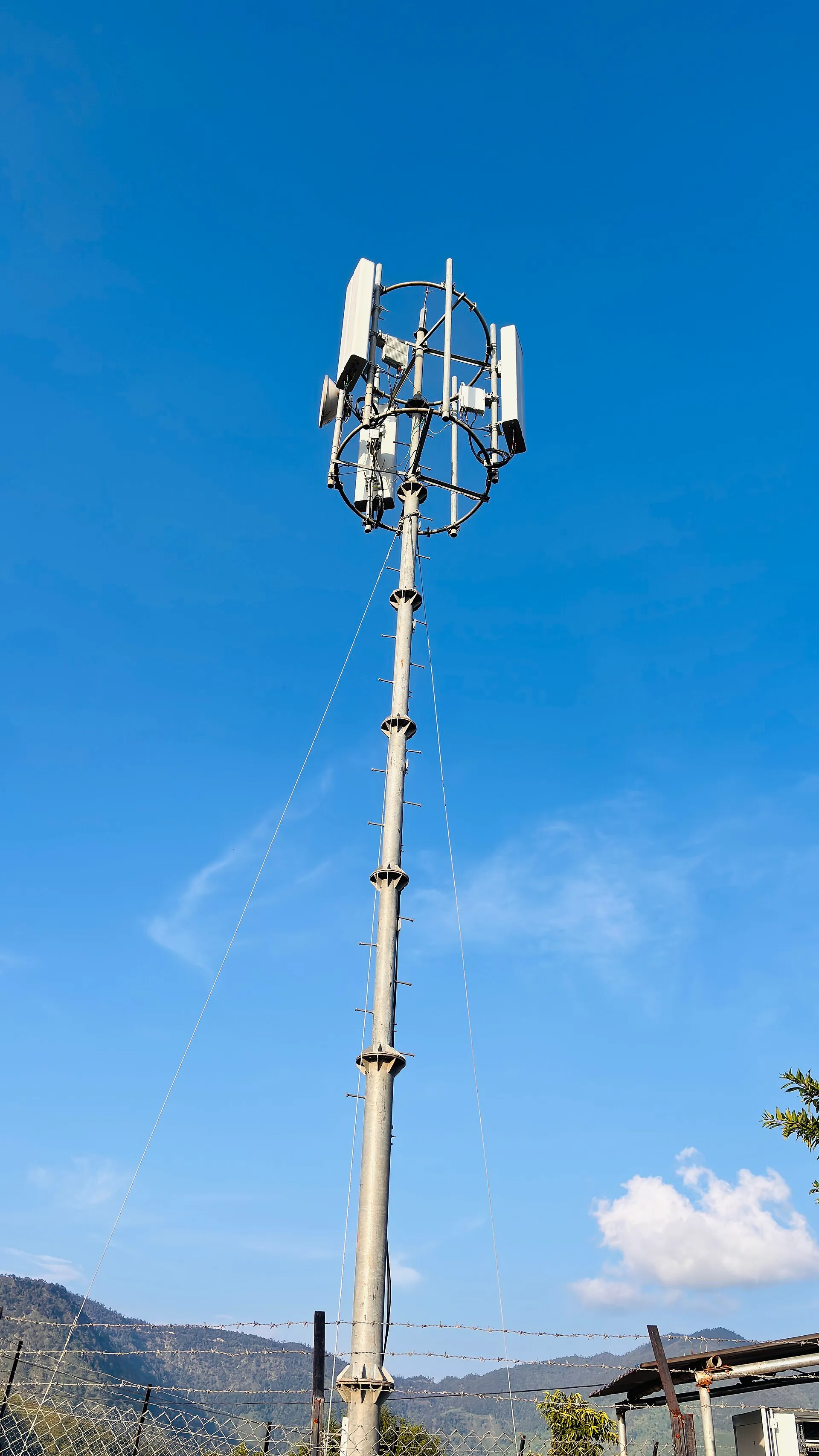 Nepal Telecom mobile tower with antennas standing against a blue sky in the hills