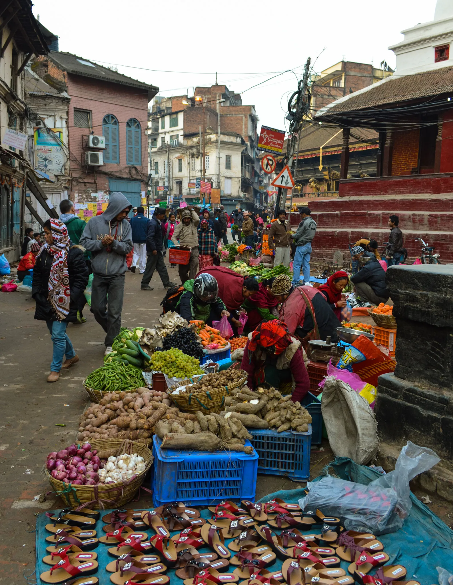 Market vendors selling vegetables and sandals on a street in Kathmandu